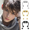 A young man models a pair of gold hoop nose rings and various piercing jewelry on his face.