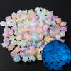 A pile of luminous glow-in-the-dark acrylic beads in various shades of pink, white, and yellow on a dark background.