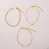 A set of handmade gold-toned crystal cross anklets displayed on a white background.
