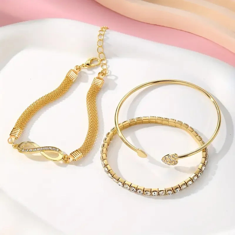 A set of three gold-toned heart charm bracelets with crystal accents displayed on a white background.