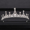 A sparkling crystal bridal crown with intricate detailing displayed on a dark surface.