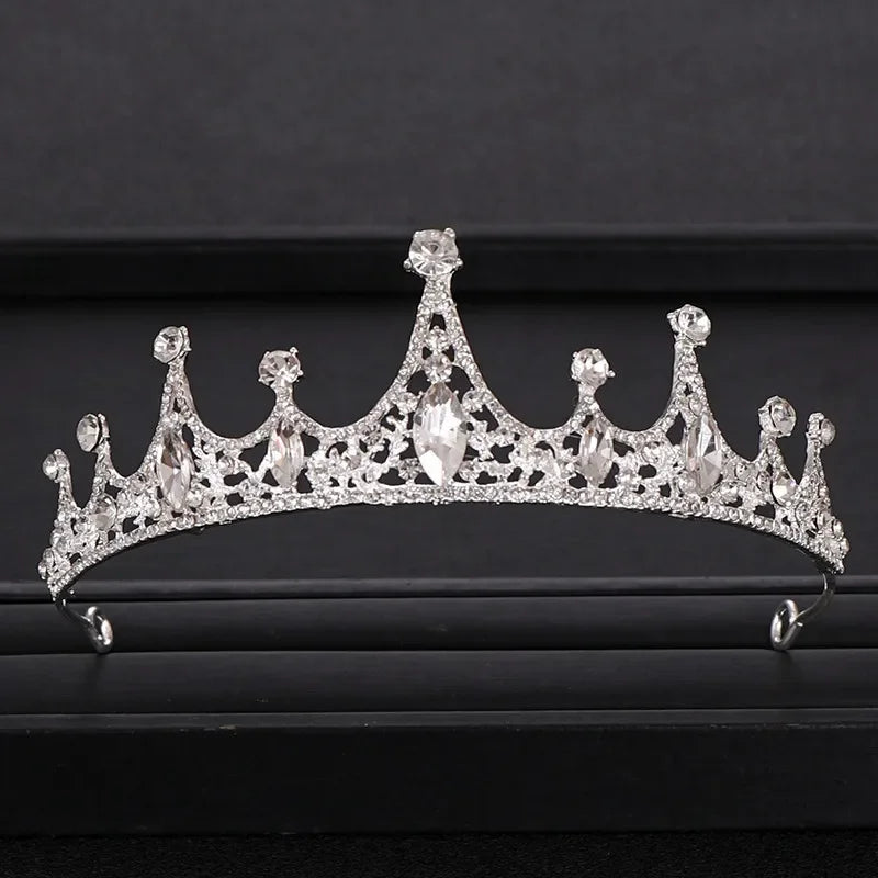 A sparkling crystal bridal crown with intricate detailing displayed on a dark surface.