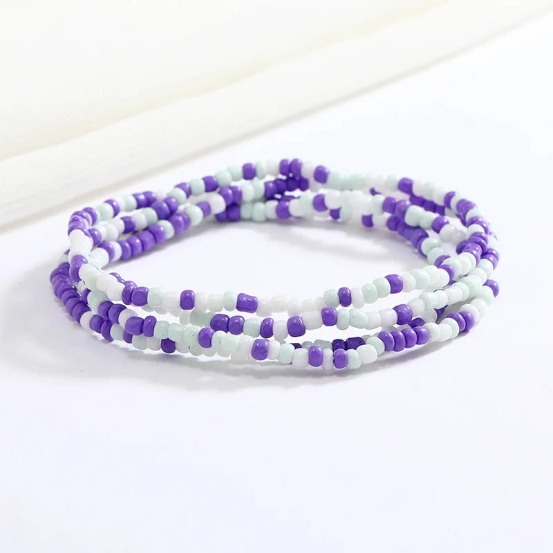 Una pulsera hecha de pequeñas cuentas moradas y blancas, enhebradas en múltiples hilos.