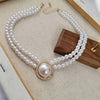 Collier délicat en perles et strass sur une surface en bois.