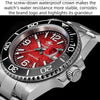 A close-up view of a silver diving watch with a red dial and a screw-down waterproof crown.