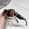 A pair of tortoiseshell patterned sunglasses with black frames being held in a hand.