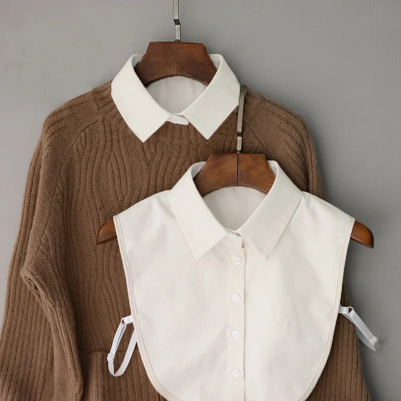 A beige knitted sweater is displayed alongside a white detachable button-up collar shirt on a wooden hanger.