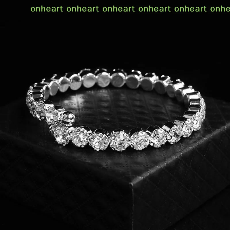 A close-up shot of a silver-toned crystal jewelry set featuring multiple rings and bracelets displayed on a dark surface.