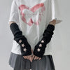 A person wearing a white t-shirt and gray skirt displays black fingerless arm warmers adorned with small star details.