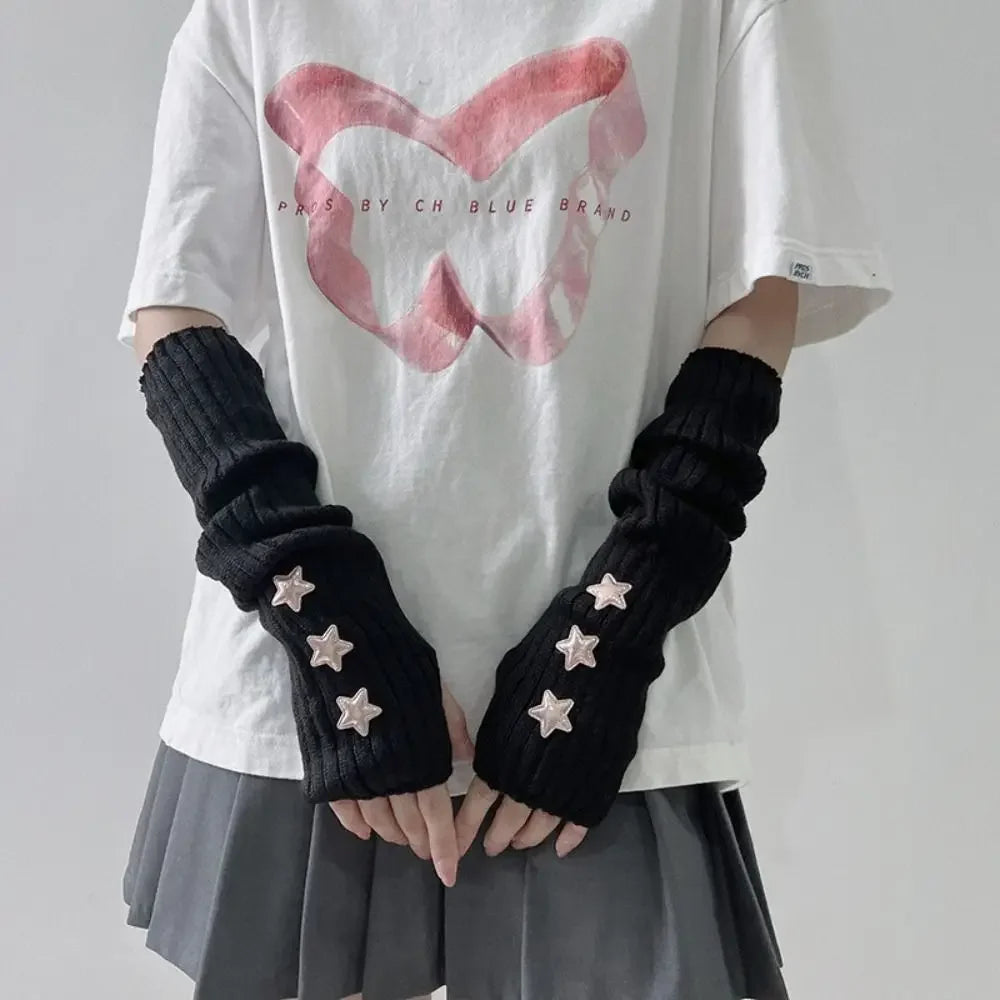 A person wearing a white t-shirt and gray skirt displays black fingerless arm warmers adorned with small star details.