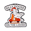 An enamel pin featuring a cartoon goose riding a small orange vehicle with the text SILLY GOOSE ON THE LOOSE