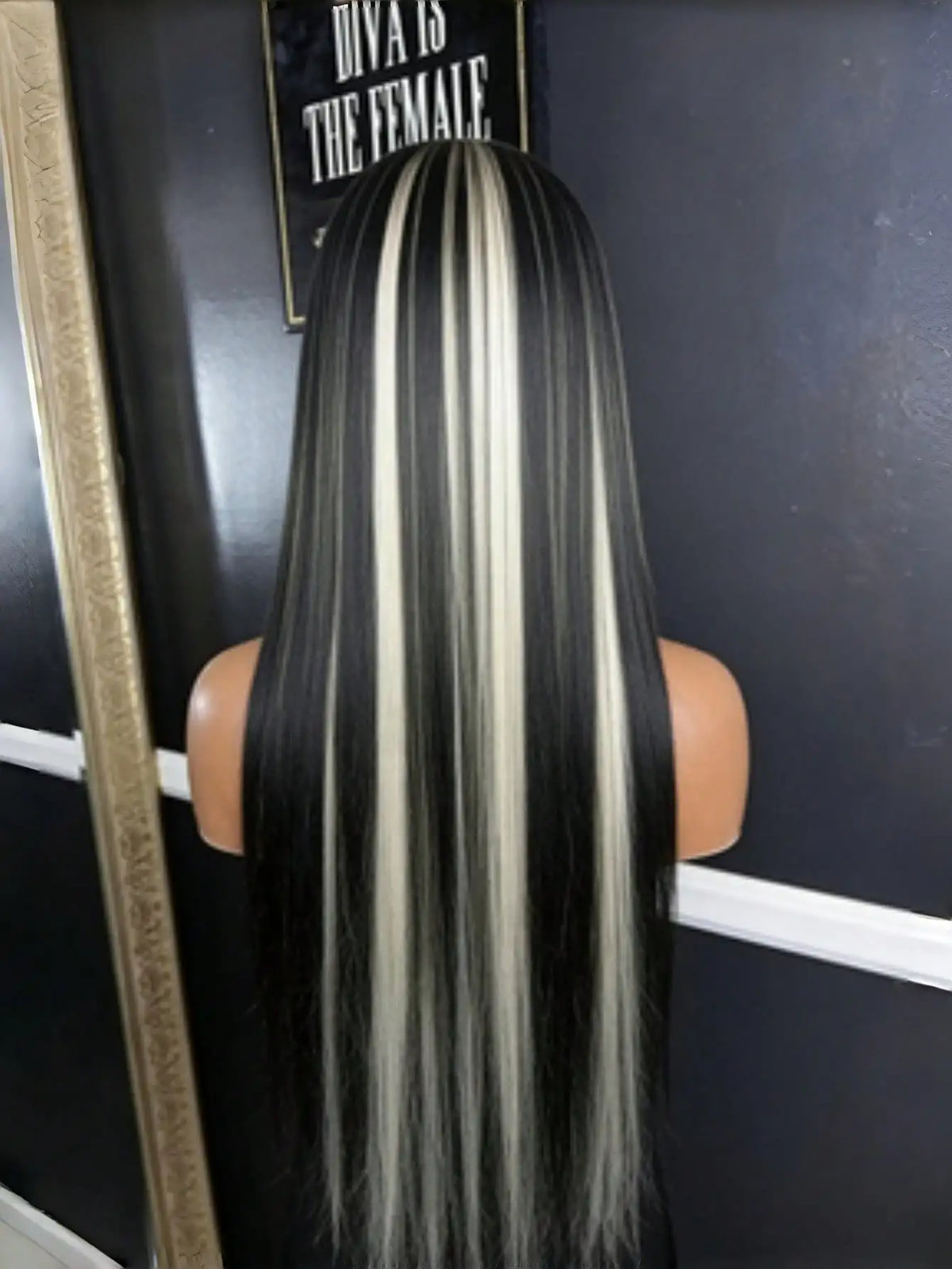 A long straight lace front wig with black and white highlights displayed against a dark background.