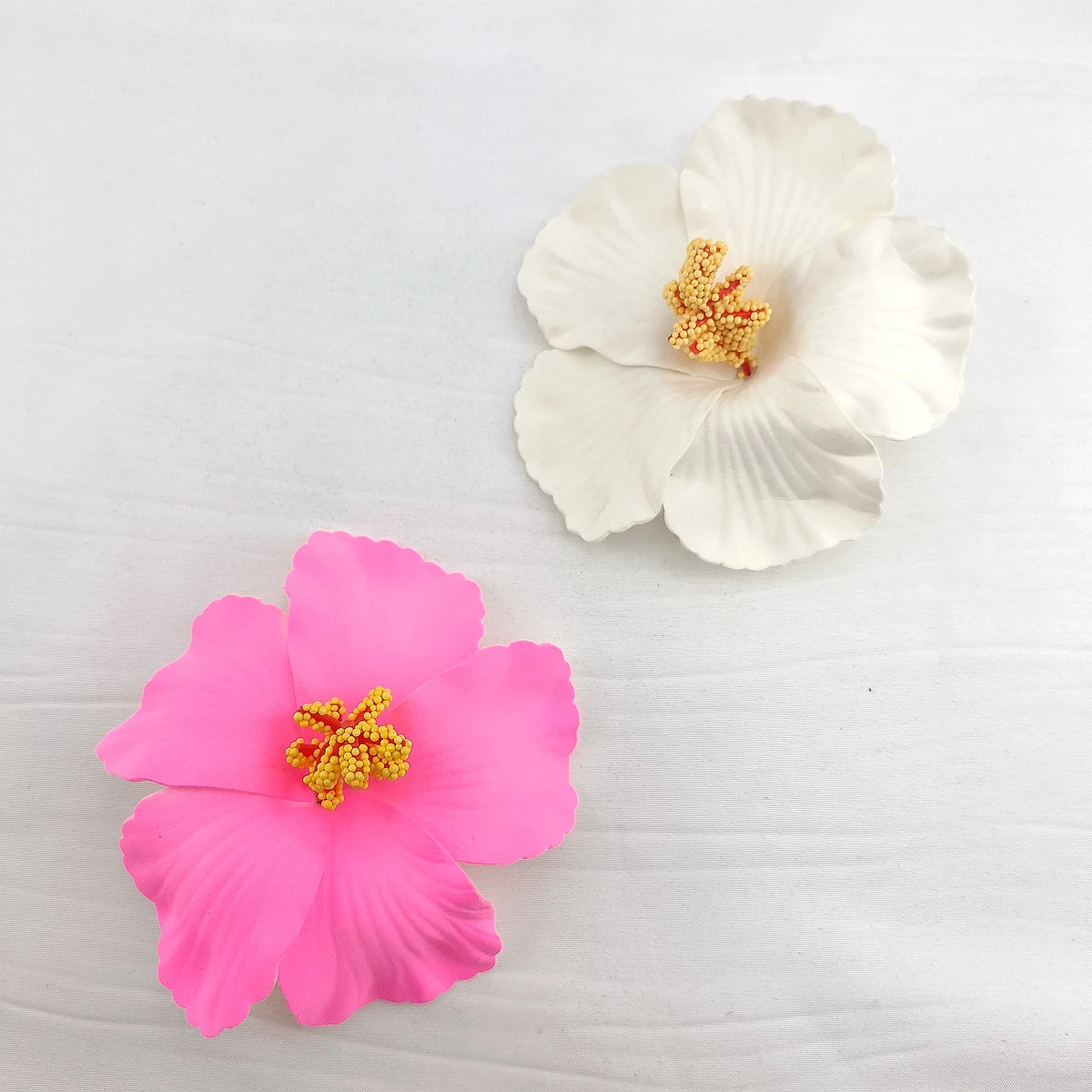 A set of delicate pink and white floral flowers used as hair clips on a white background.