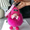 A pink fluffy plush doll with a pink hat and bow is shown being held by a hand.