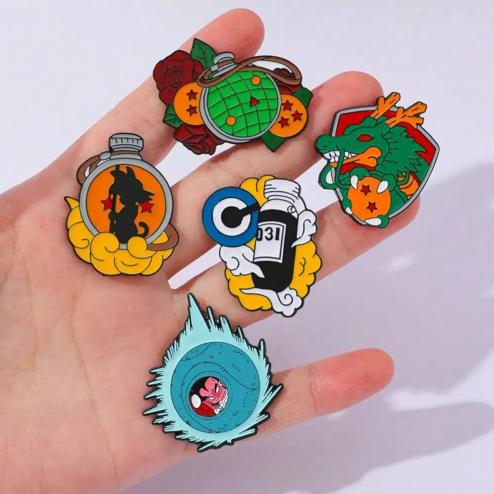 Eine Hand hält eine Sammlung von 12 Emaille-Pins mit कार्टून-Charakteren und Designs von Son Goku Master Roshi.