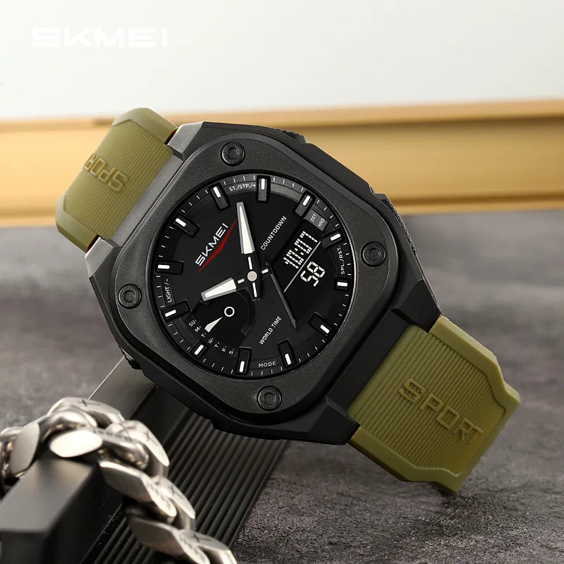 A black and olive green digital sports watch is shown on a dark surface next to a silver chain.