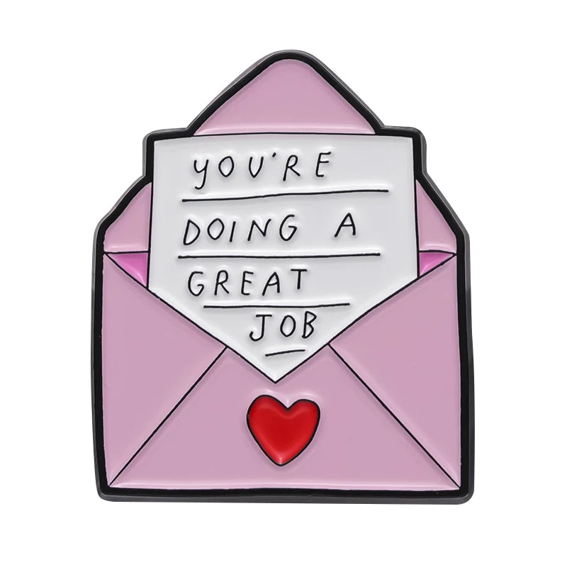 A pink envelope shaped enamel pin featuring the text You're doing a great job and a red heart detail.