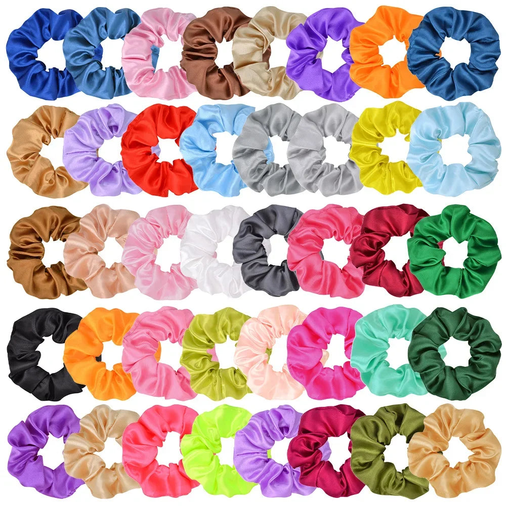 A collection of colorful satin scrunchies in various shades including blue, pink, orange, and green.