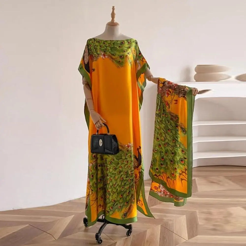 Une femme portant un châle cape orange long et fluide avec un imprimé de papillon et de paon floral vert, exposé sur un manne