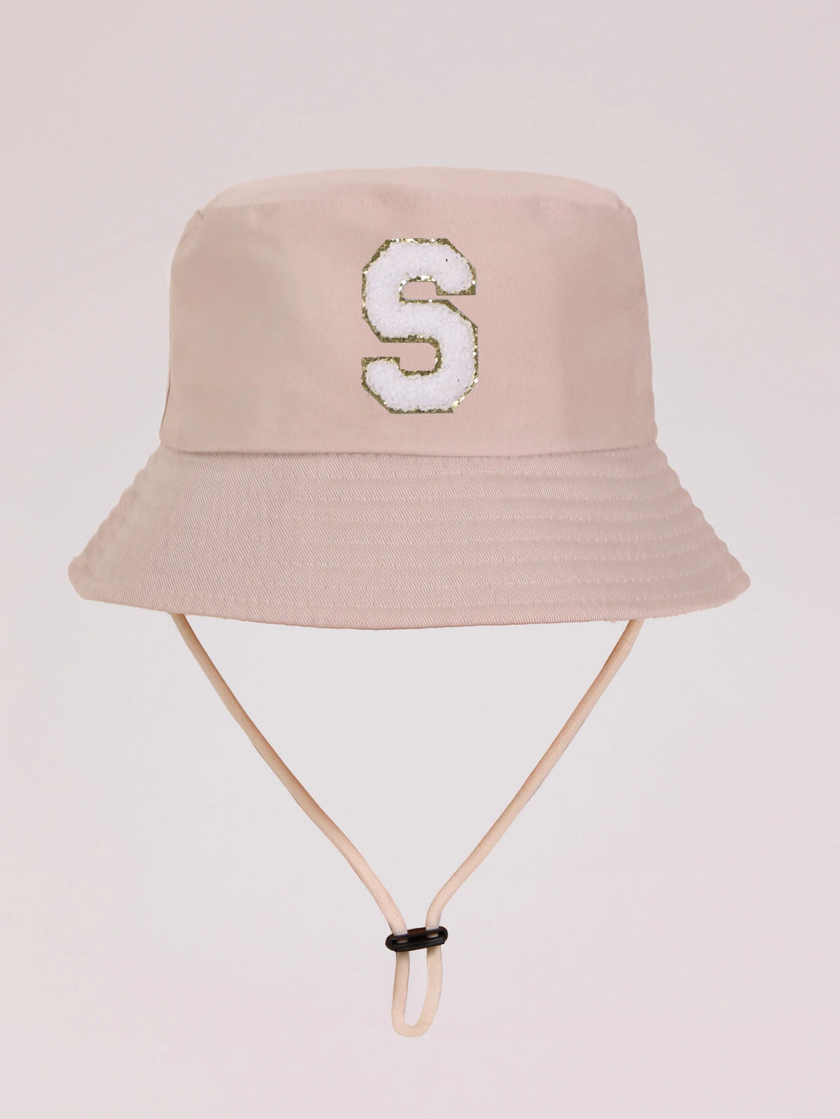 A light beige sun hat with a white embroidered letter S on the front