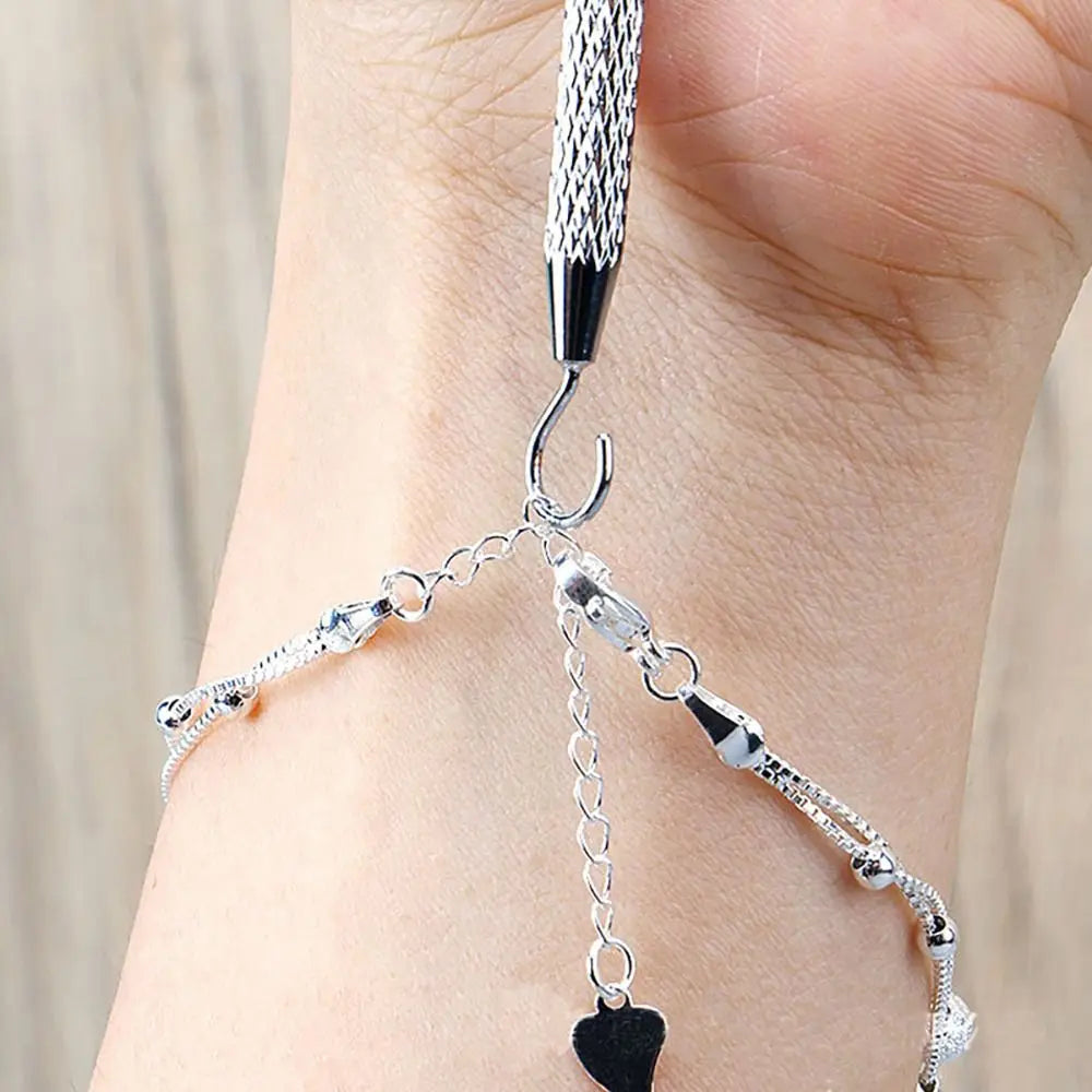 Gros plan d'une main portant une pince à bijoux argentée sur un poignet.