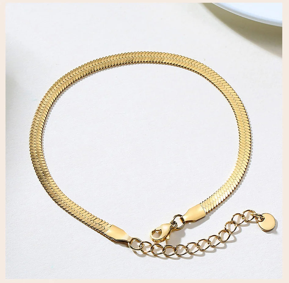 A gold-toned stainless steel snake chain anklet worn on a wrist, displayed against a white background.
