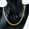 A close-up of an elegant gold plated necklace set for women displayed on a black mannequin.
