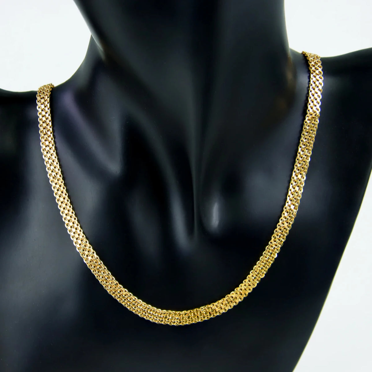 A close-up of an elegant gold plated necklace set for women displayed on a black mannequin.
