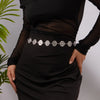 A woman wearing a silver heart waist chain body jewelry over a black dress.