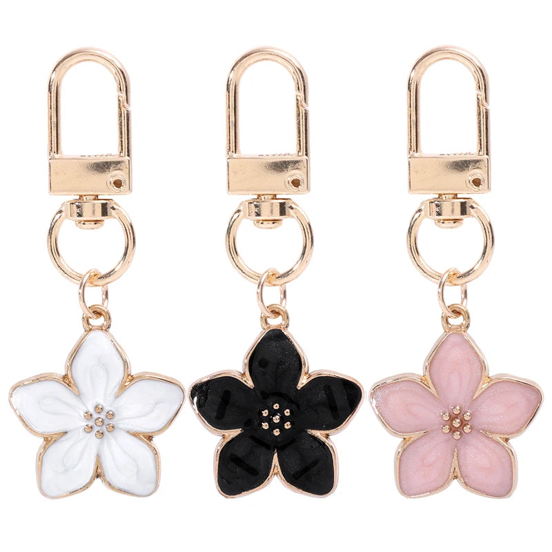 Un juego de tres llaveros florales en blanco, negro y rosa.