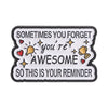A black enamel pin with white text that reads Sometimes you forget you're awesome so this is your reminder