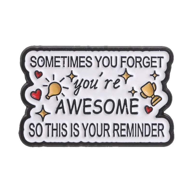 A black enamel pin with white text that reads Sometimes you forget you're awesome so this is your reminder