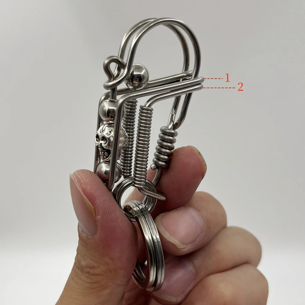 Une main tient un porte-clés mécanique en acier inoxydable avec un crâne et des ressorts enroulés.