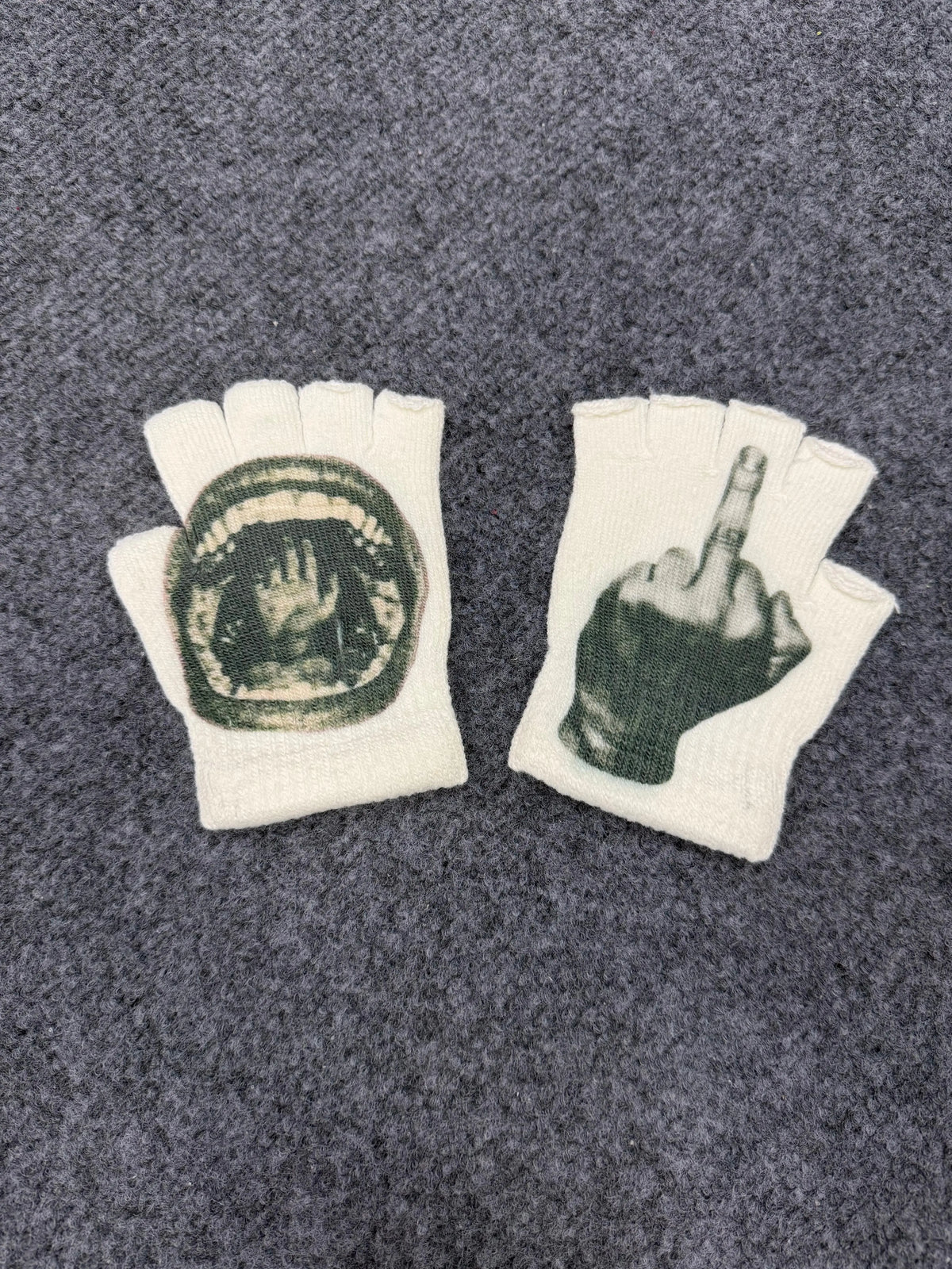Pair of white fingerless knit gloves with a dark print of a hand and a finger pointing