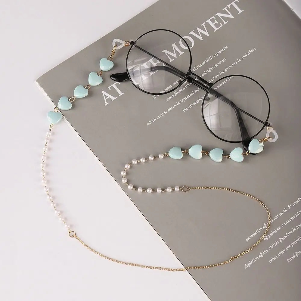 Gold-toned pearl beaded eyewear chains displayed on a gray card with text.