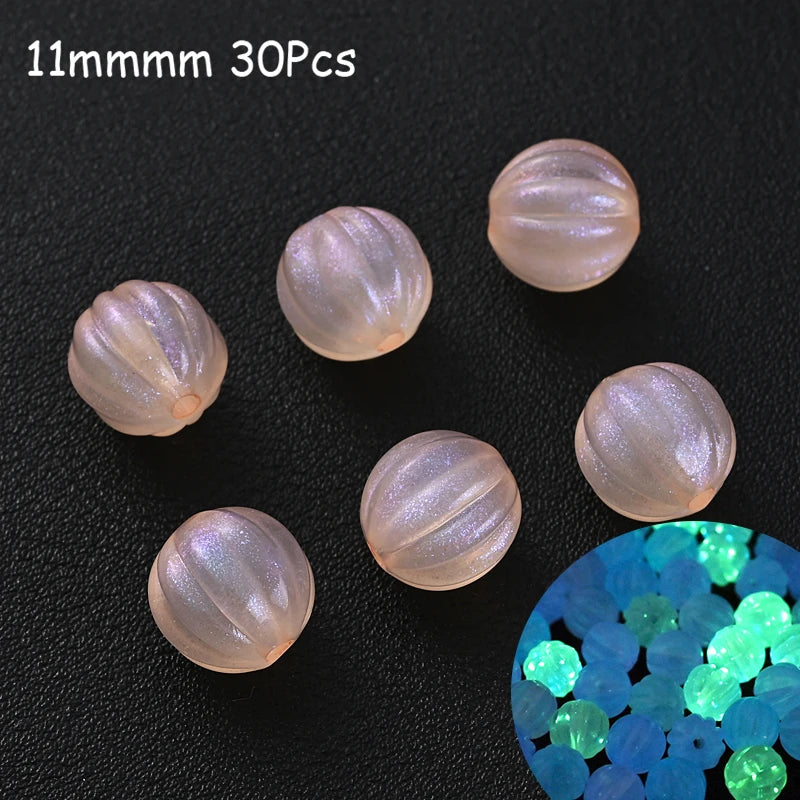 Thirty 11mm luminous glow-in-the-dark acrylic beads scattered on a dark surface with a cluster of blue and green beads.