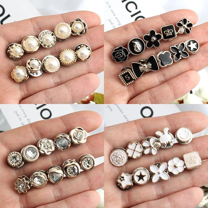 A collection of elegant button brooch pins featuring various floral and geometric designs in silver and black enamel.